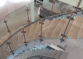 Custom curved glass and stainless steel railing around a staircase